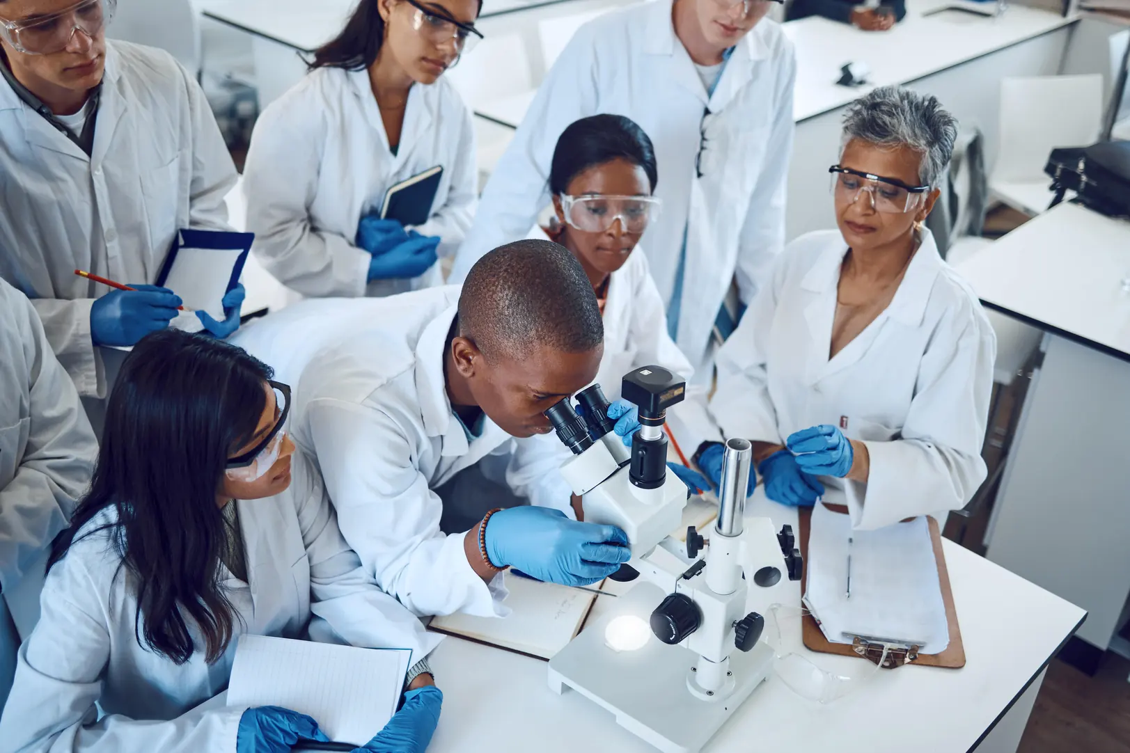 Grupo de estudantes de ciências em laboratório universitário usando microscópio