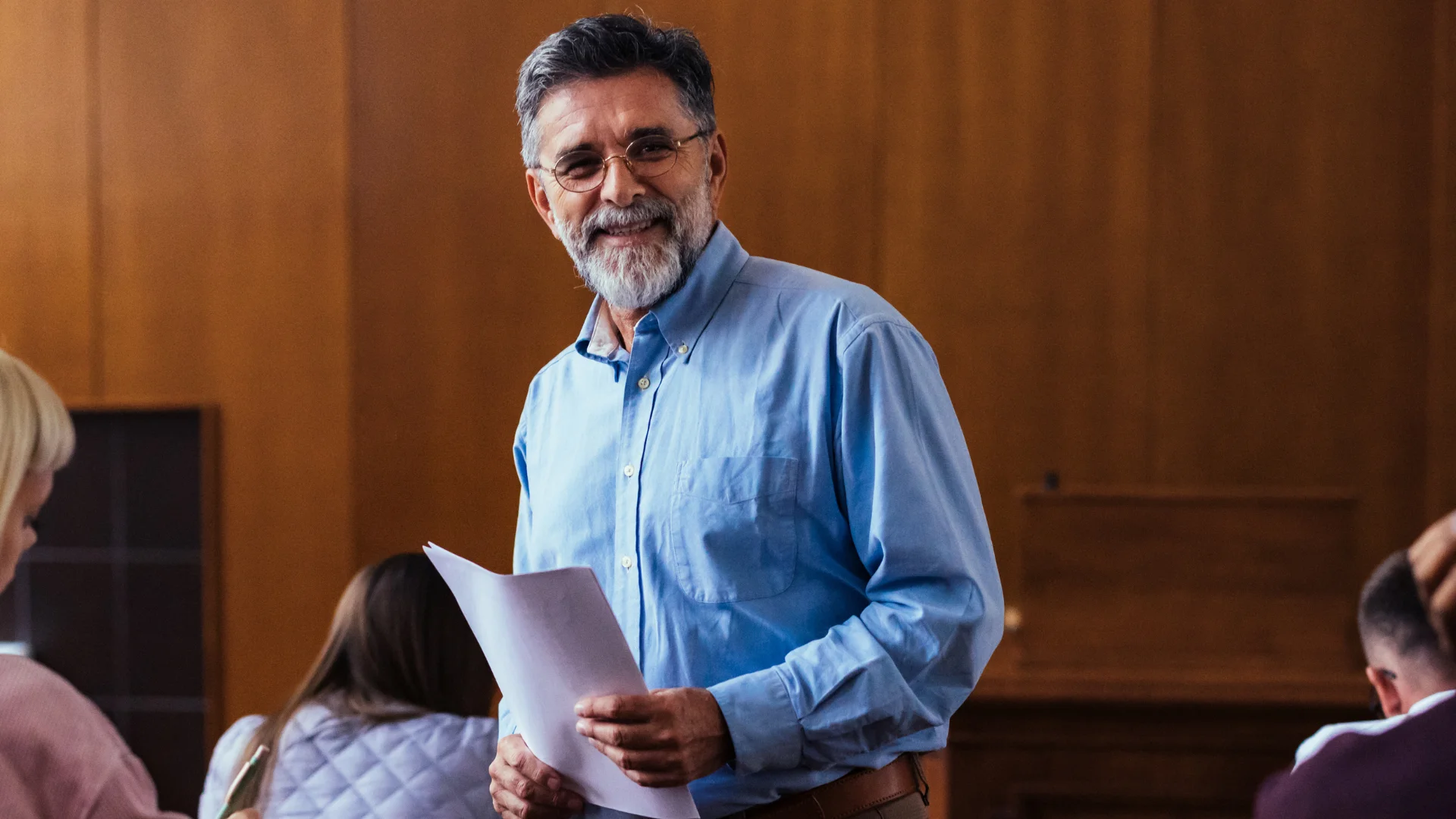 Professor universitário sênior sorrindo com papéis em sala de aula