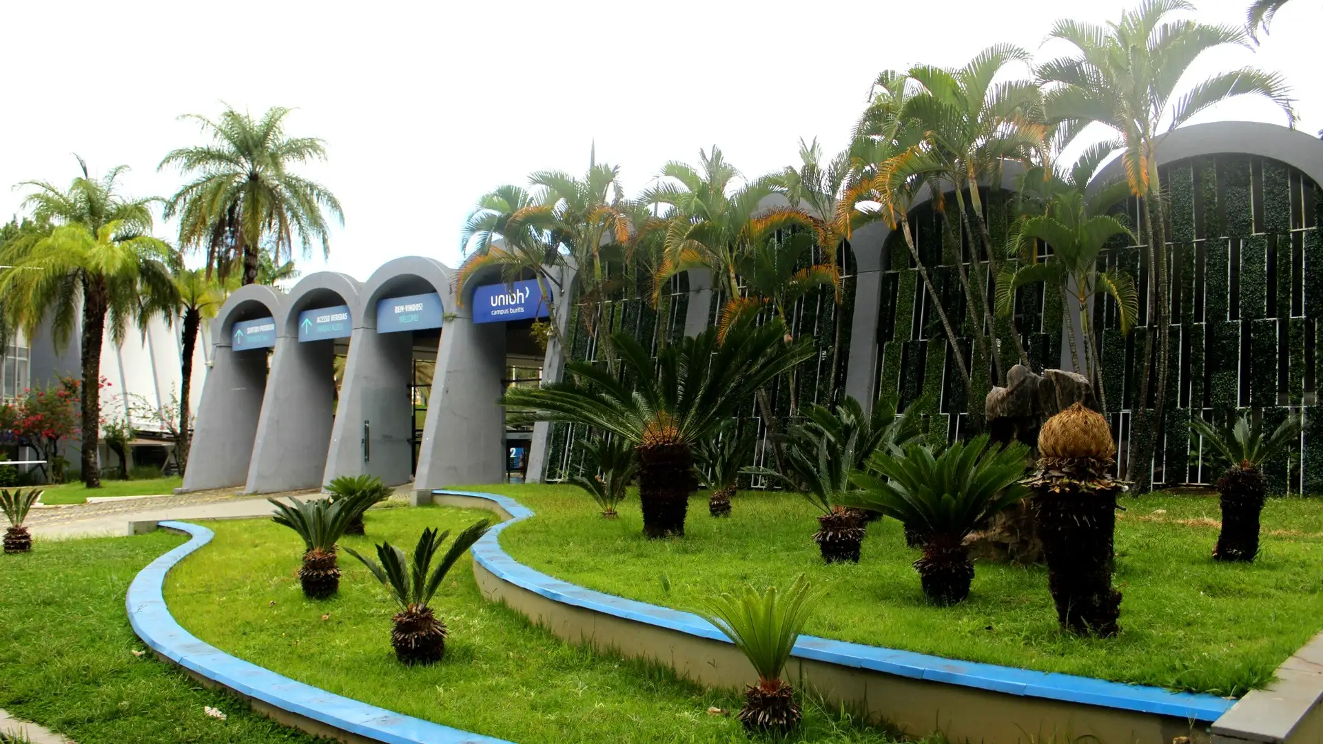Fachada moderna do campus Buritis da UniBH com jardim e palmeiras