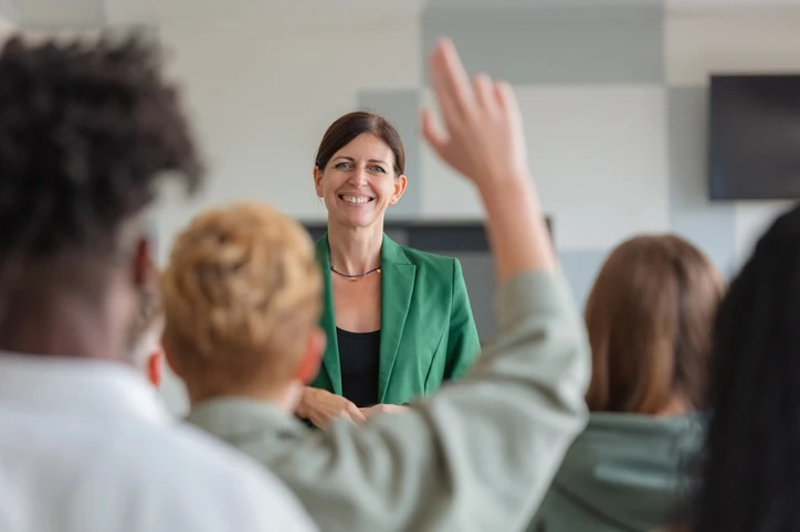 Professora conduzindo aula interativa com alunos participativos em ambiente de ensino superior moderno