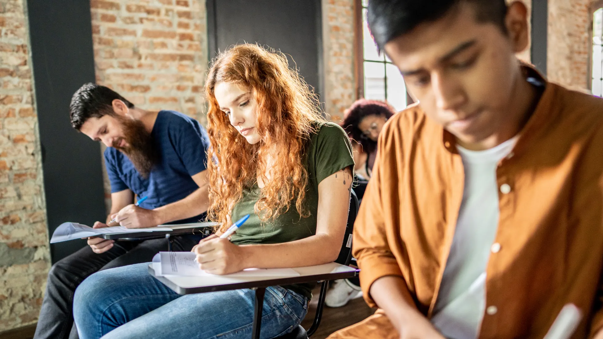 Grupo de estudantes universitários concentrados realizando uma prova importante em uma sala de aula moderna