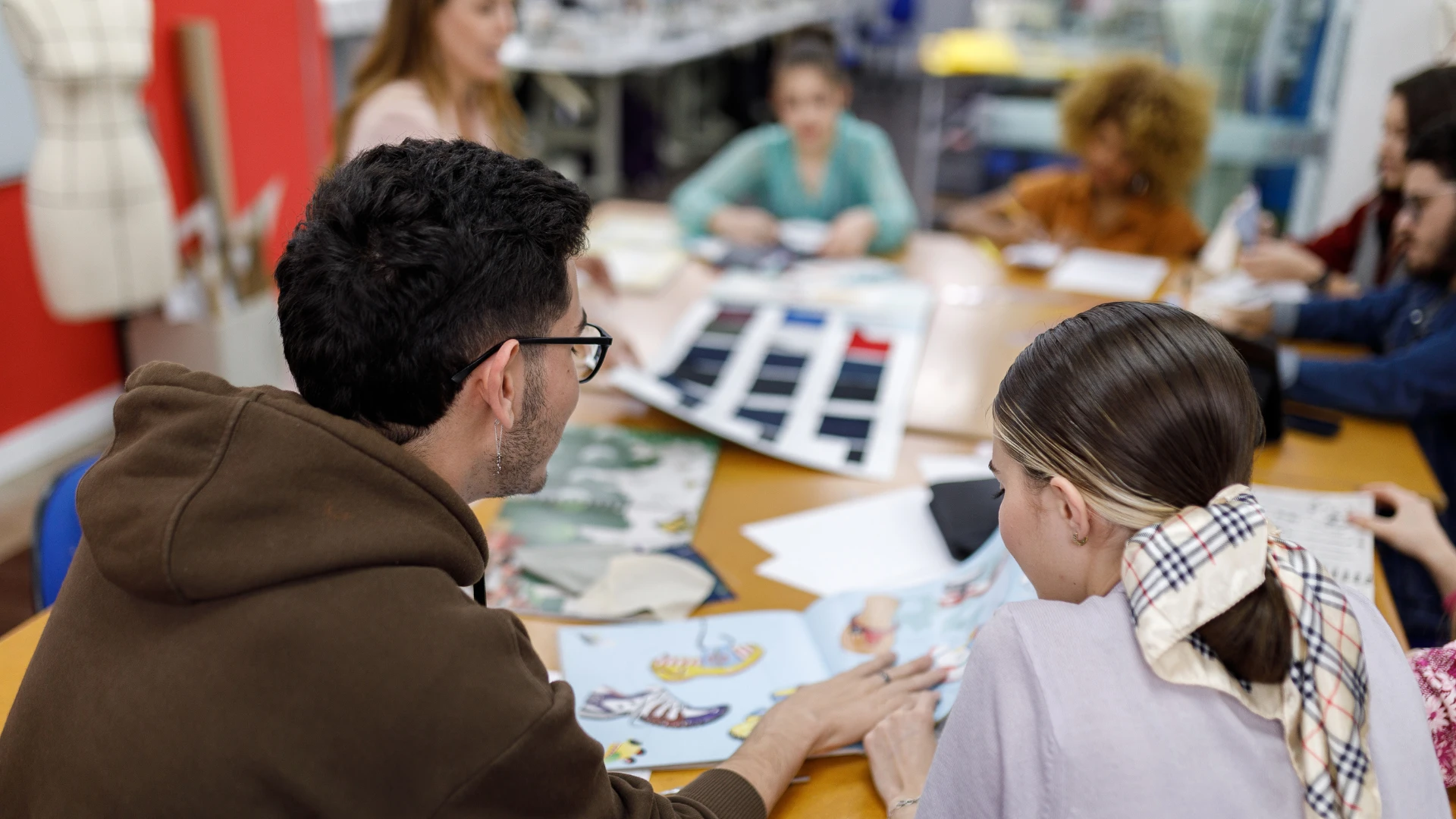 Estudantes de design de moda colaborando em um projeto em sala de aula