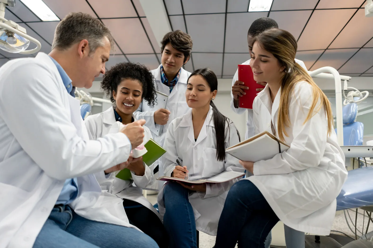 Aula prática de odontologia com professor orientando estudantes de graduação sobre saúde bucal em um ambiente universitário
