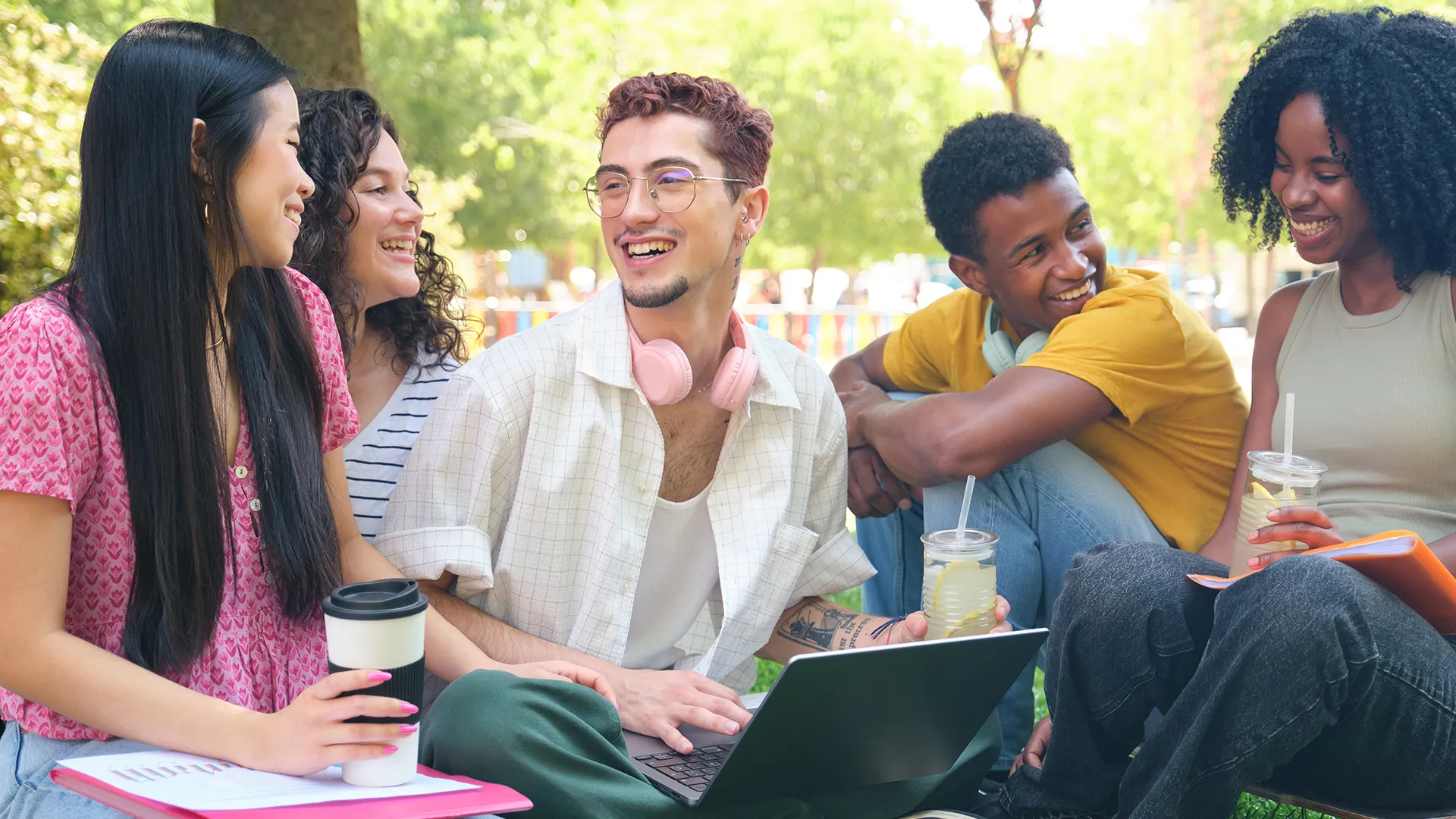Grupo de estudantes universitários diversos conversando e estudando ao ar livre em um campus ensolarado
