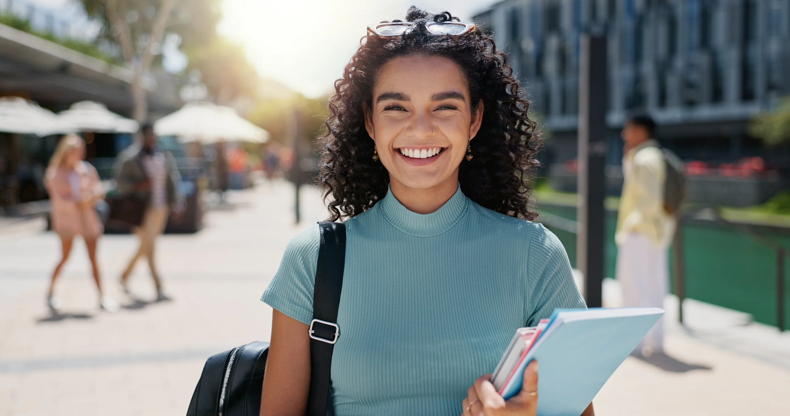 Estudante universitária jovem e sorridente segurando cadernos no campus