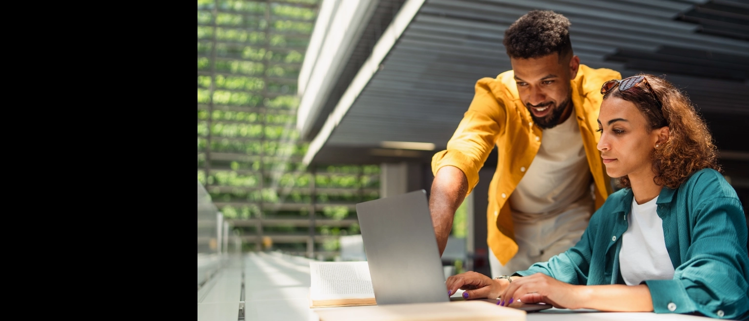 Estudantes universitários trabalhando juntos em um projeto de pesquisa acadêmica utilizando um laptop em um ambiente de estudo colaborativo