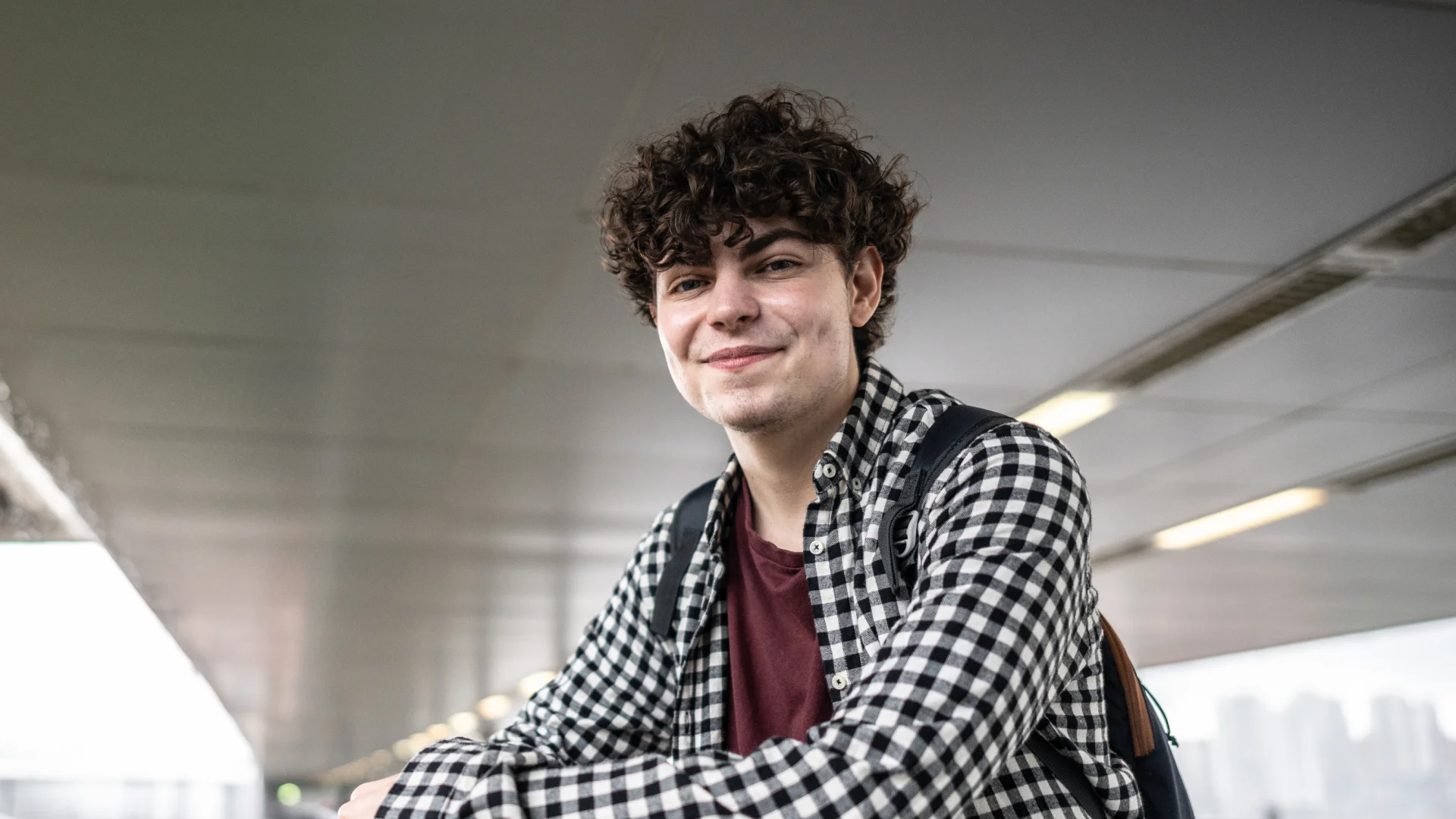 Retrato de um jovem estudante universitário sorridente com mochila em um campus ou ambiente educacional