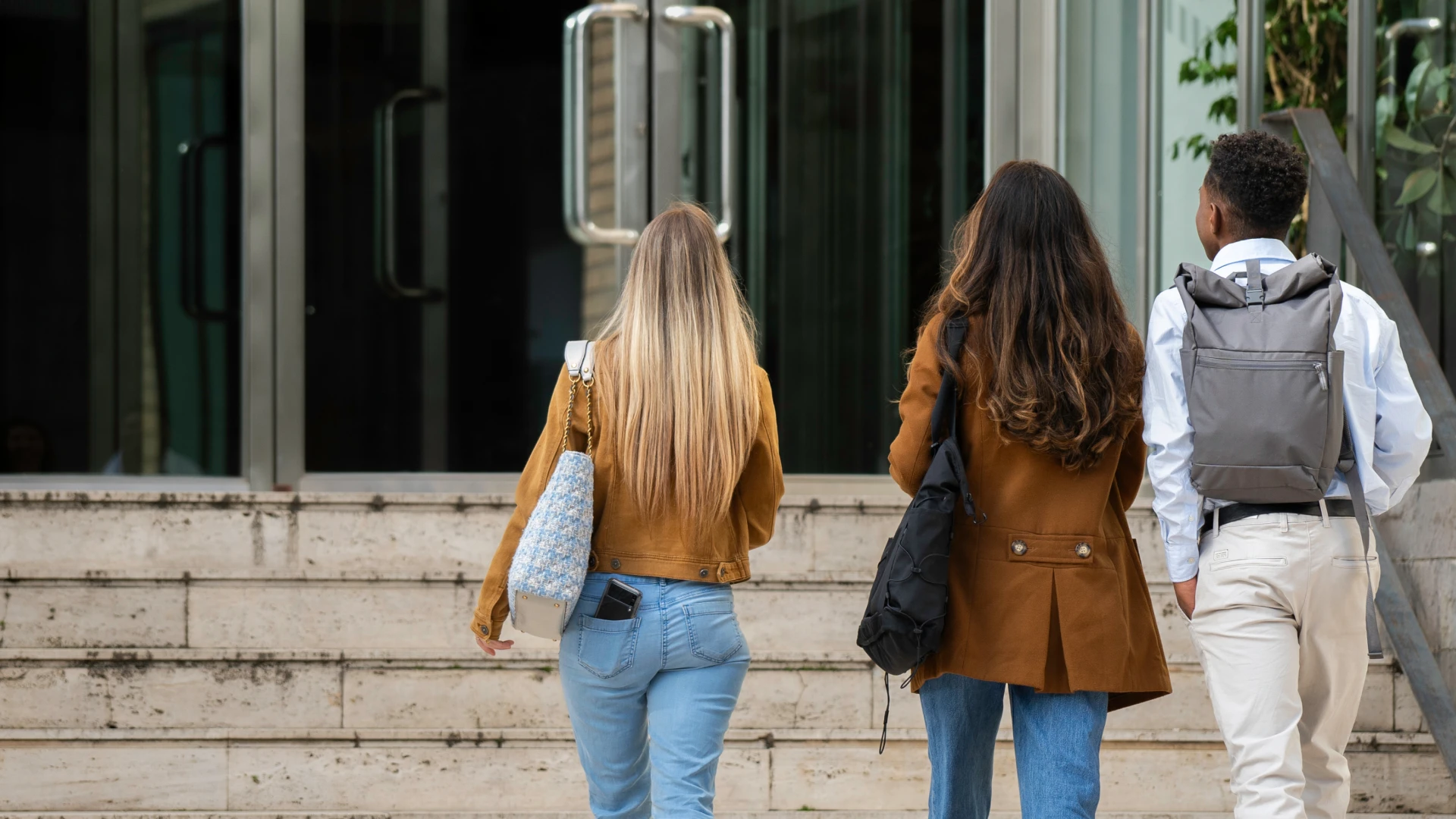 Estudantes universitários diversos chegando para aula em um campus moderno com ambiente acadêmico acolhedor