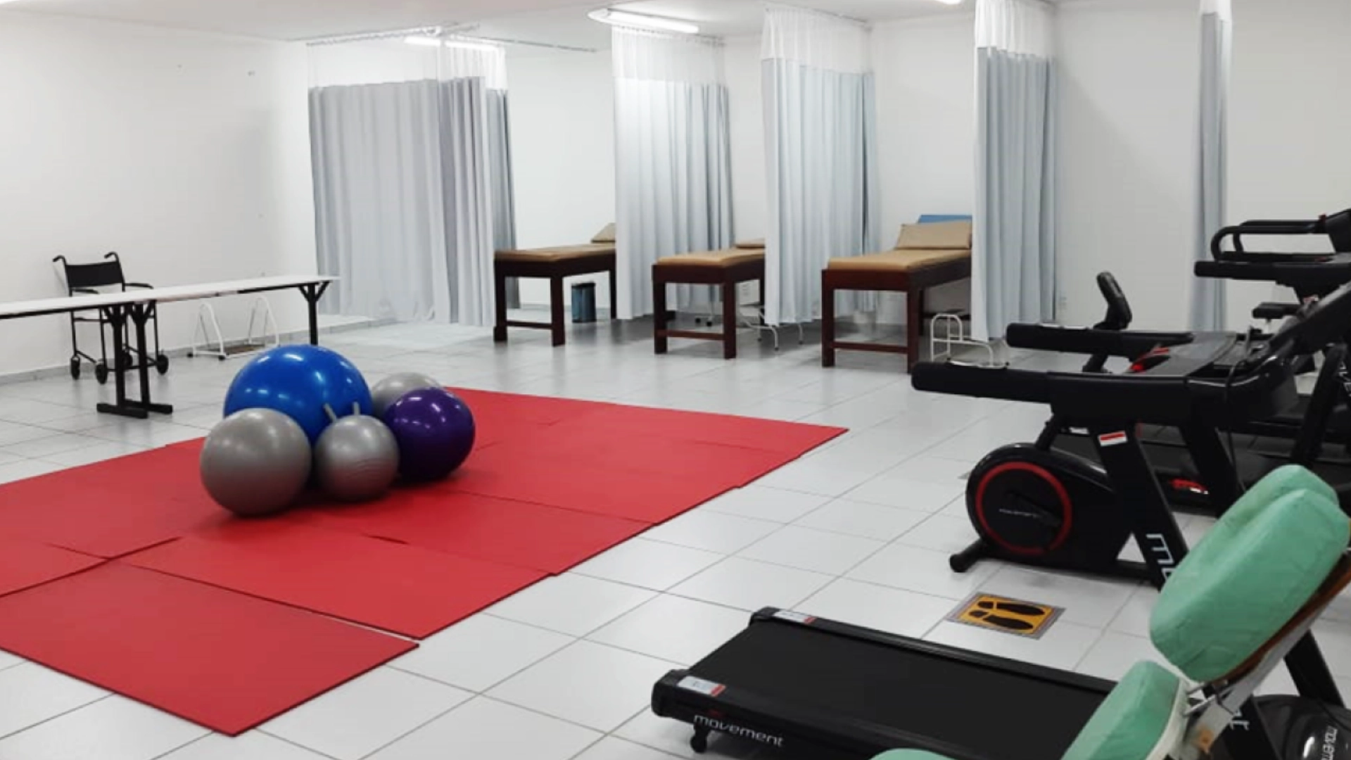 Laboratório de fisioterapia com macas, bolas de pilates e equipamentos de ginástica