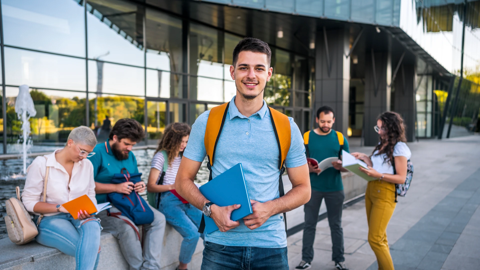 Jovem estudante universitário sorridente em um campus moderno cercado por colegas de classe estudando ao ar livre