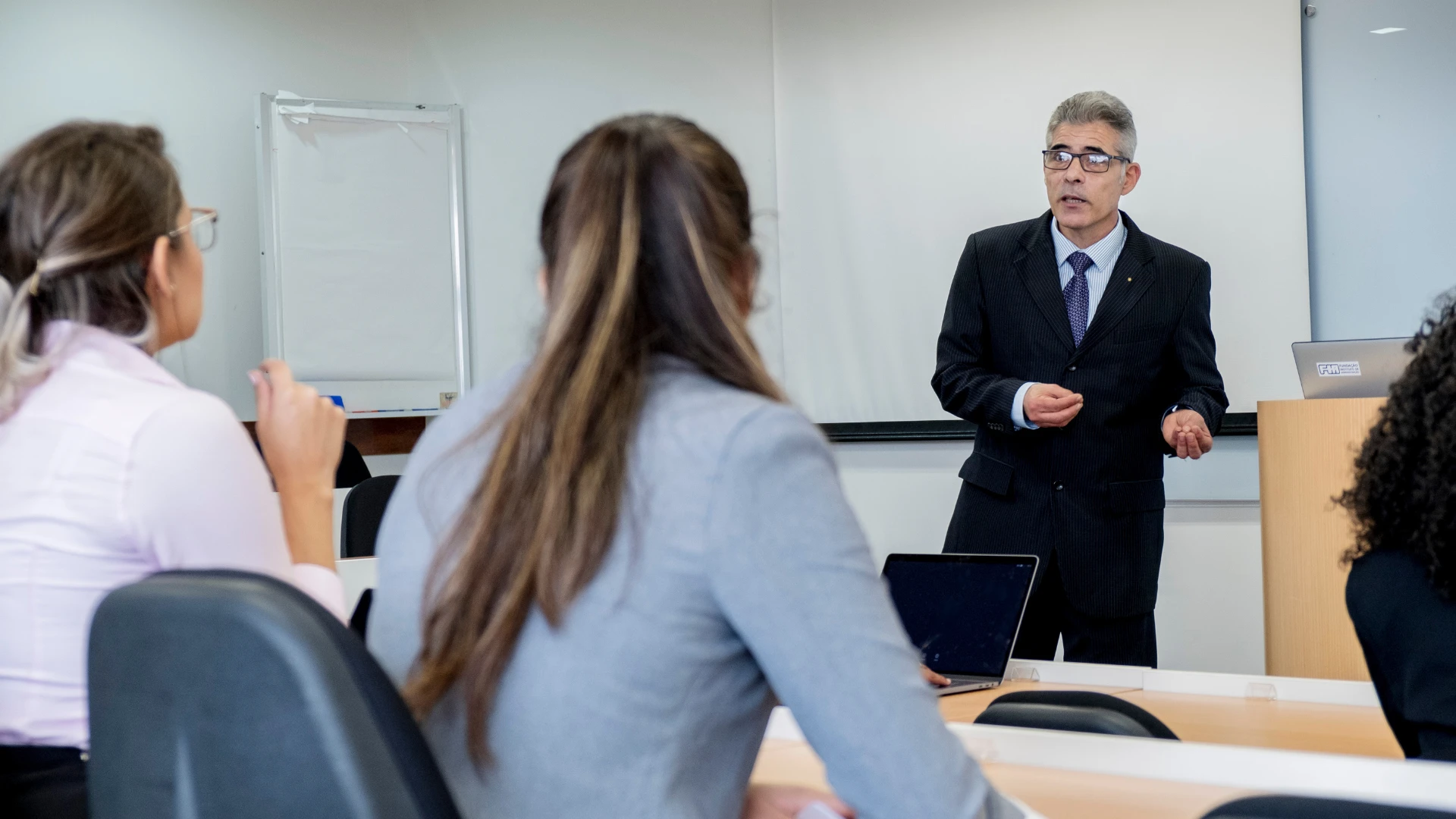 Professor experiente ministrando palestra ou aula para estudantes em ambiente de ensino superior