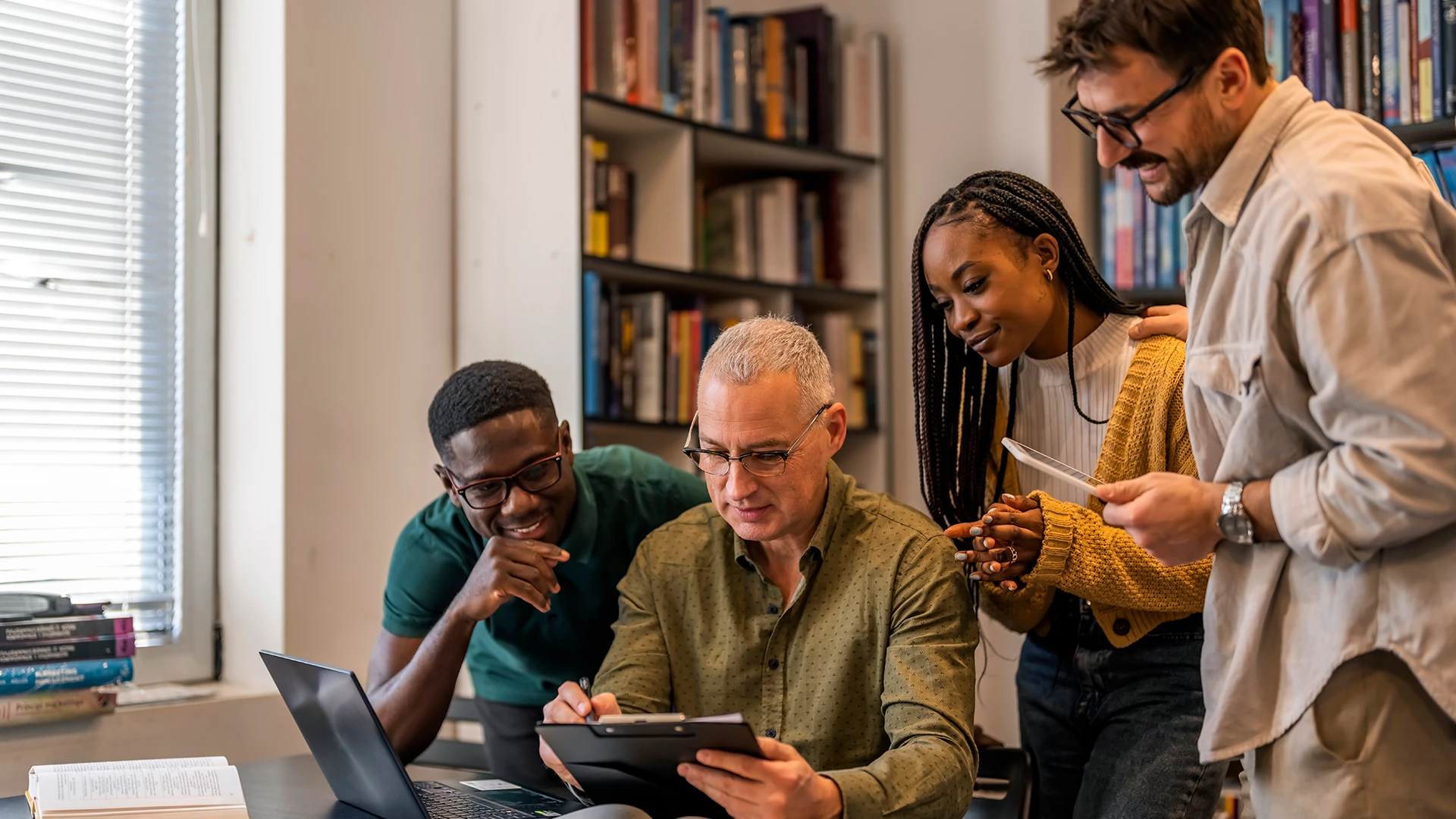 Grupo diversificado de estudantes e professor colaborando em um projeto acadêmico em uma biblioteca