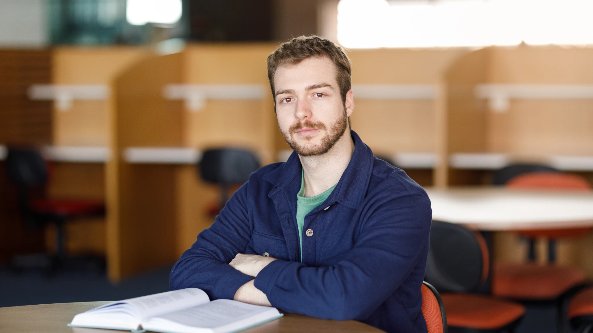 Estudante universitário sentado em uma biblioteca com um livro aberto