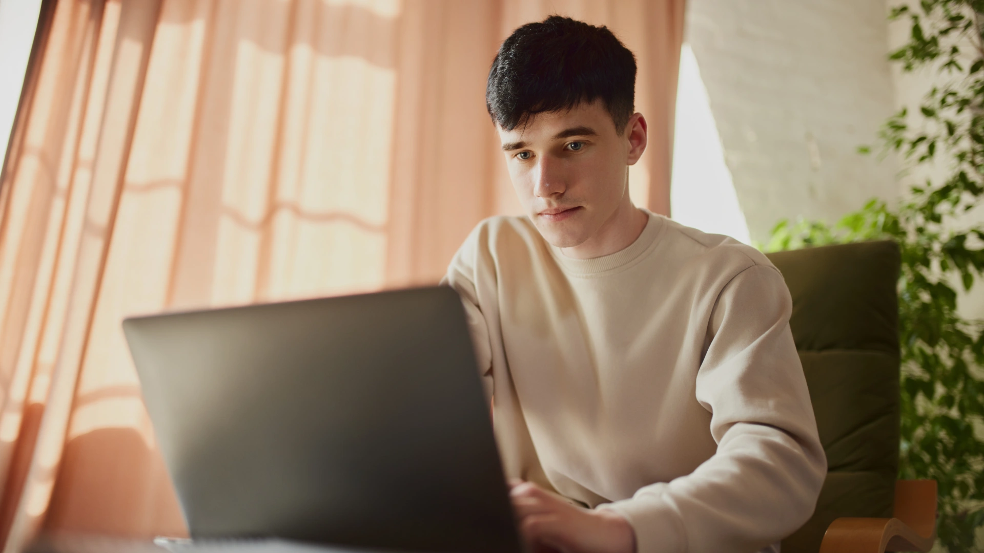 Jovem estudante focado utilizando notebook para atividades acadêmicas ou trabalho remoto