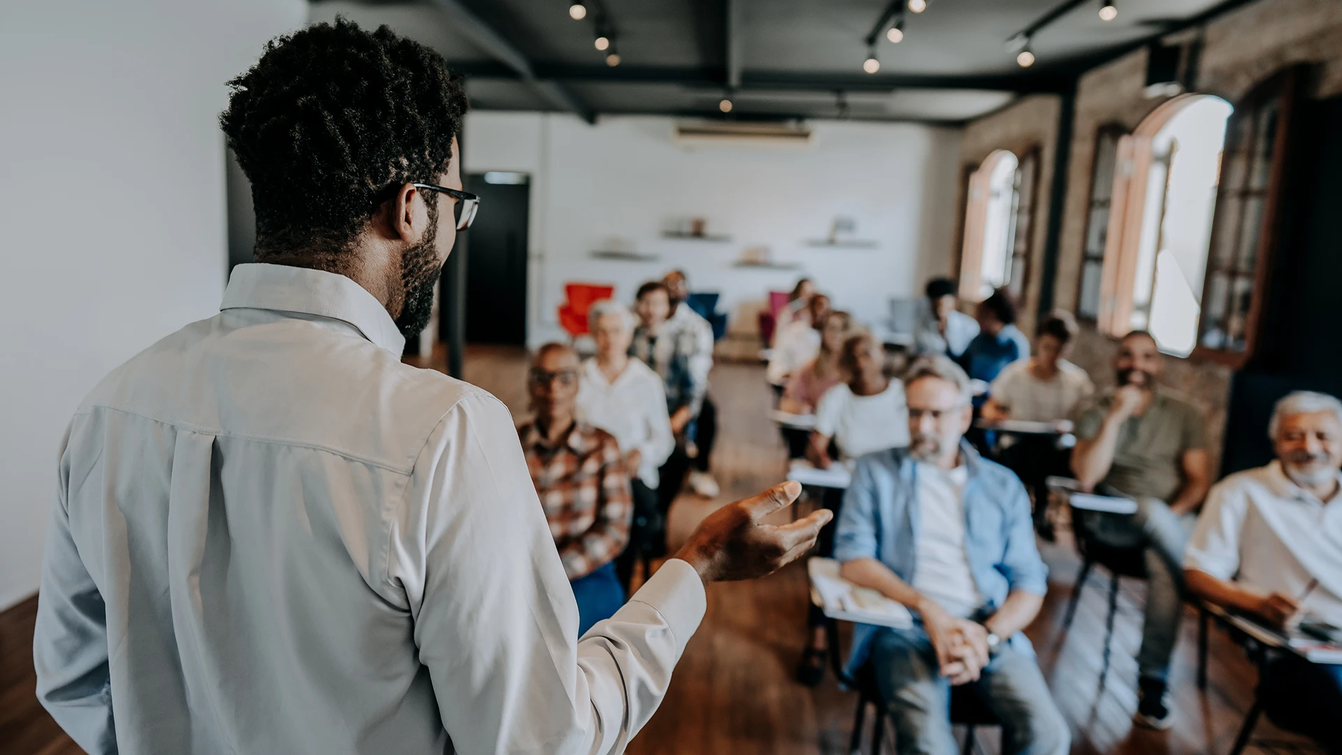 Professor ministrando palestra para uma turma diversificada em sala de aula moderna