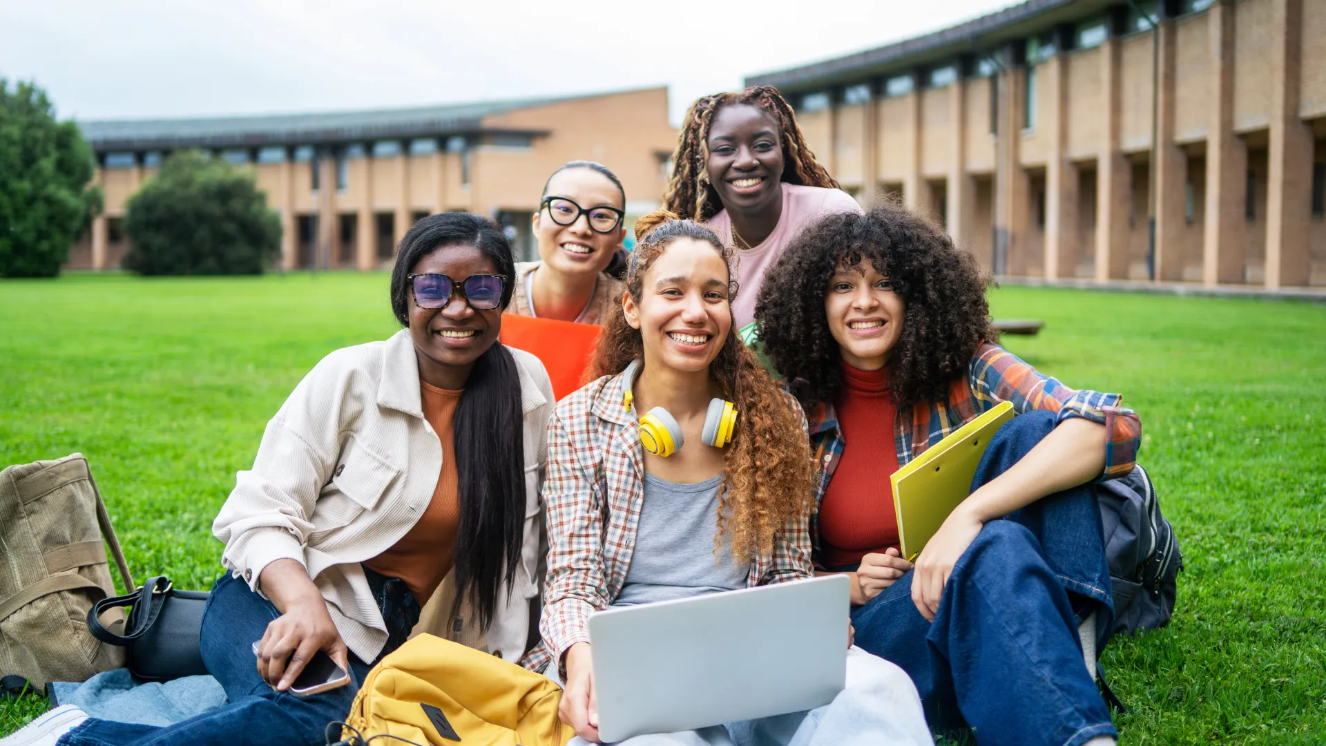 Estudantes universitários diversos reunidos em um campus ensolarado para estudo em grupo e colaboração acadêmica