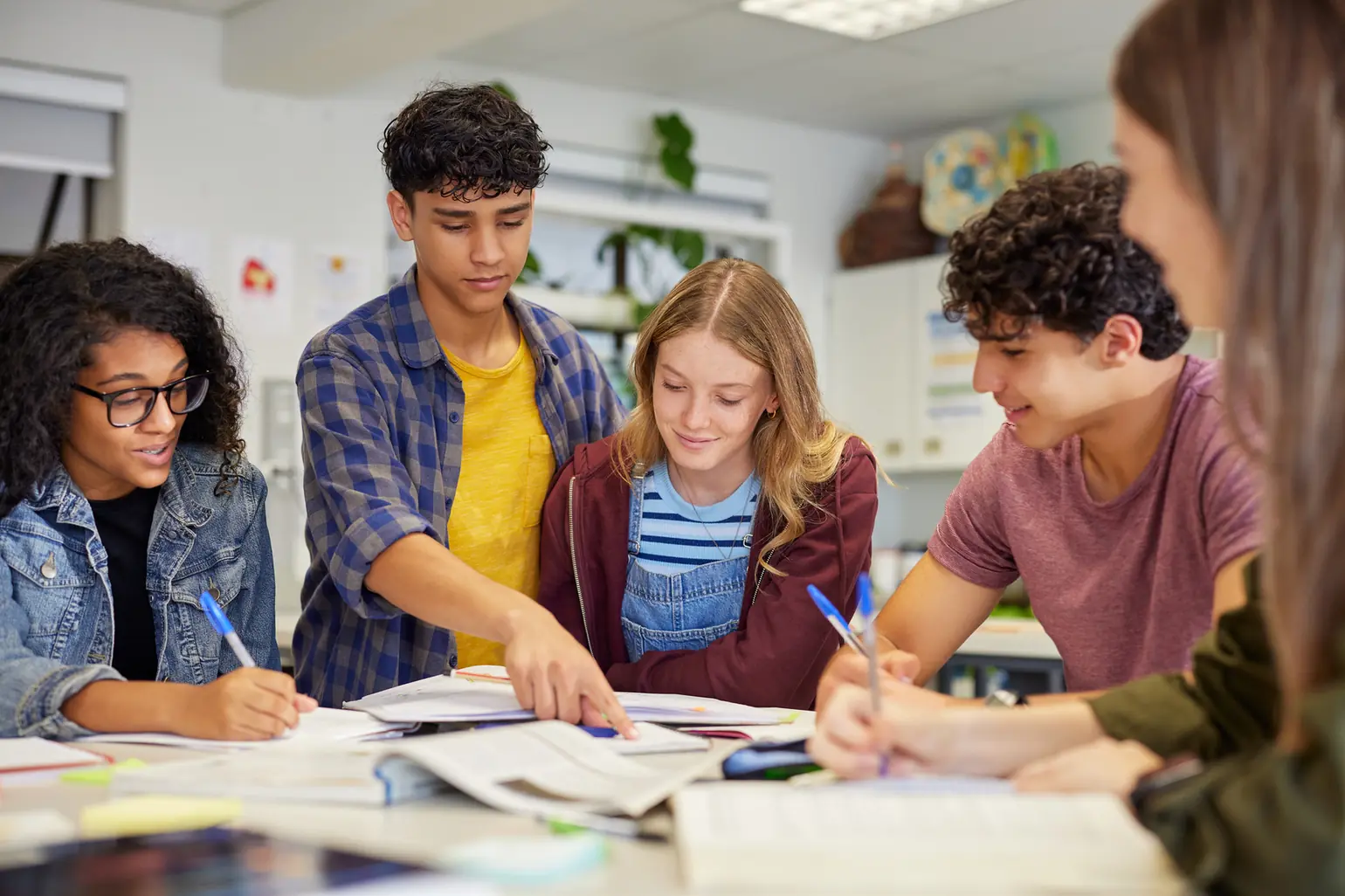 Grupo de estudantes universitários diversos estudando juntos em uma mesa de biblioteca