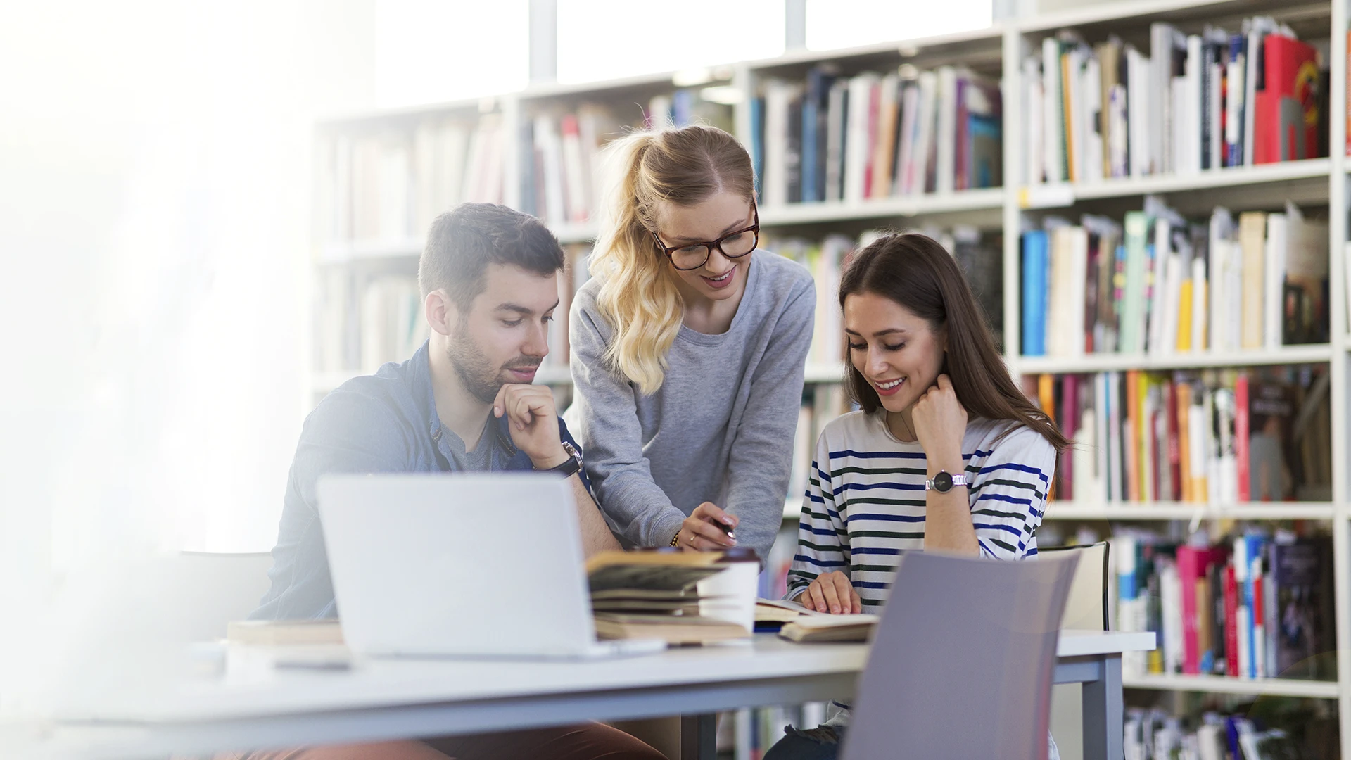 Estudantes universitários trabalhando juntos em um projeto de pesquisa na biblioteca