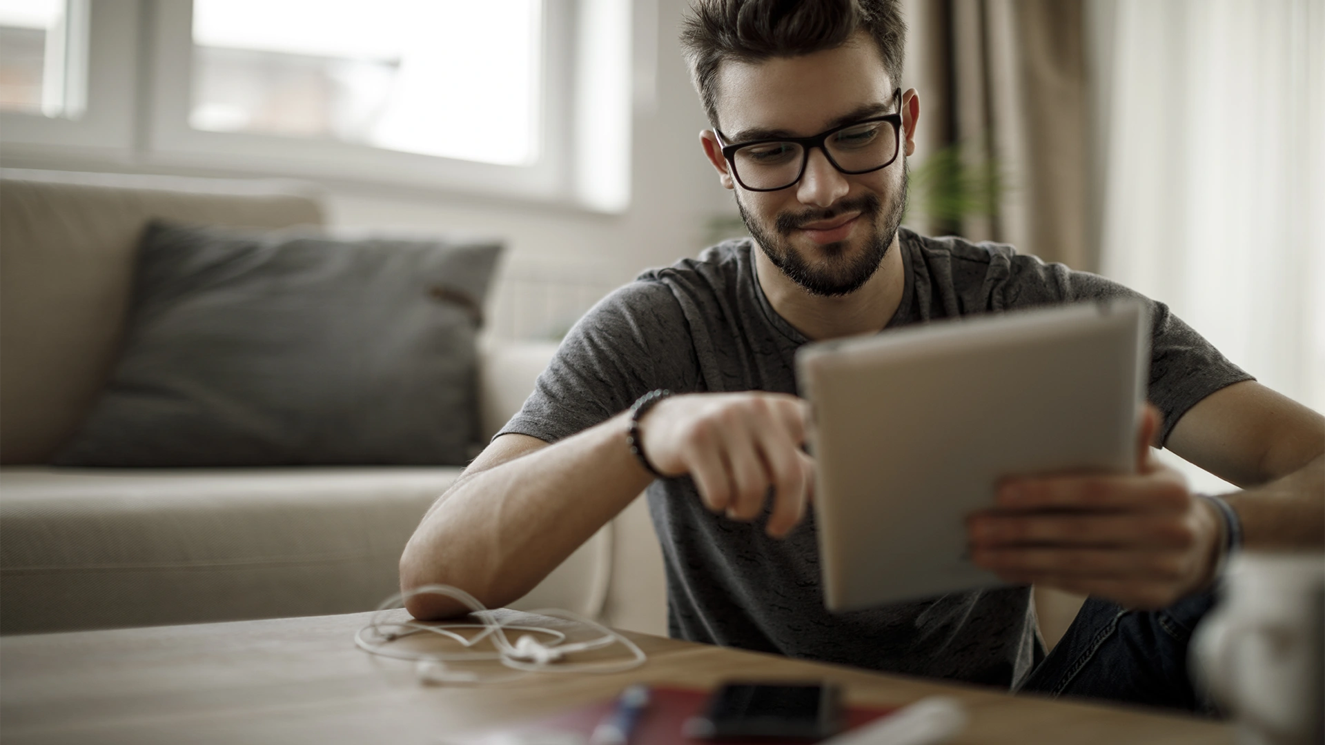 Jovem estudante de óculos usando tablet para estudo online em casa