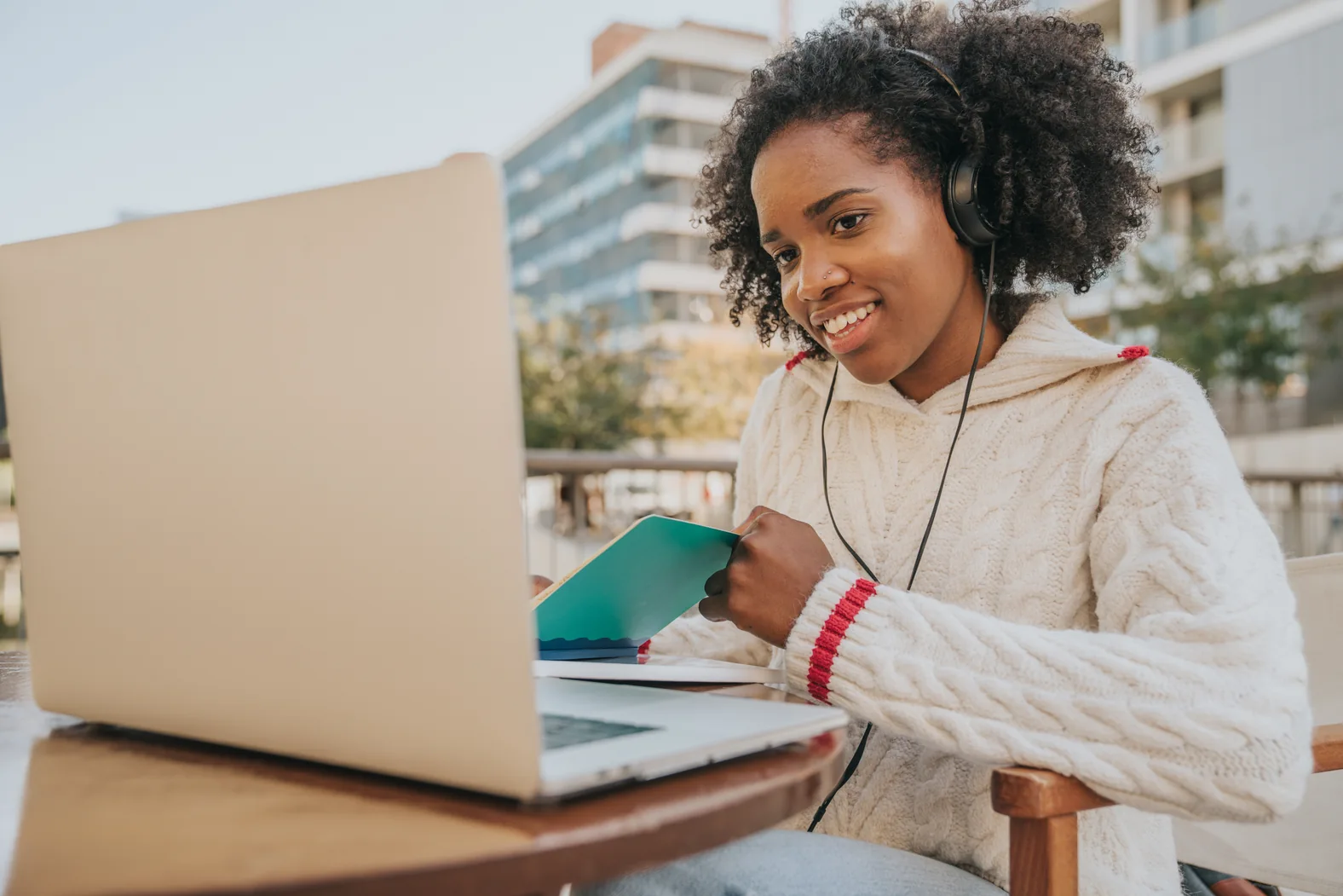 Young female student using a laptop and credit card outside on campus