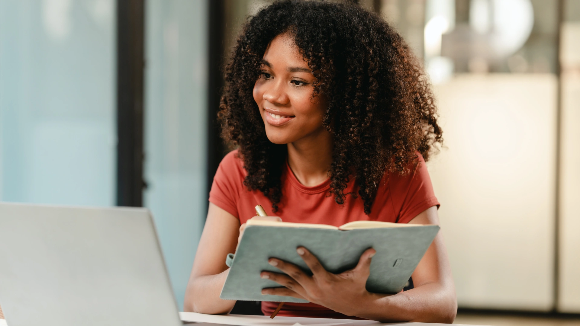 Estudante universitária focada em seus estudos online utilizando notebook e caderno para anotações