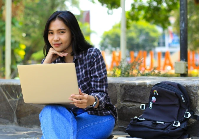 Estudante universitária utilizando laptop ao ar livre no campus